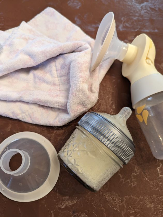burp cloth, electric pump, flanges, bottle of breast milk