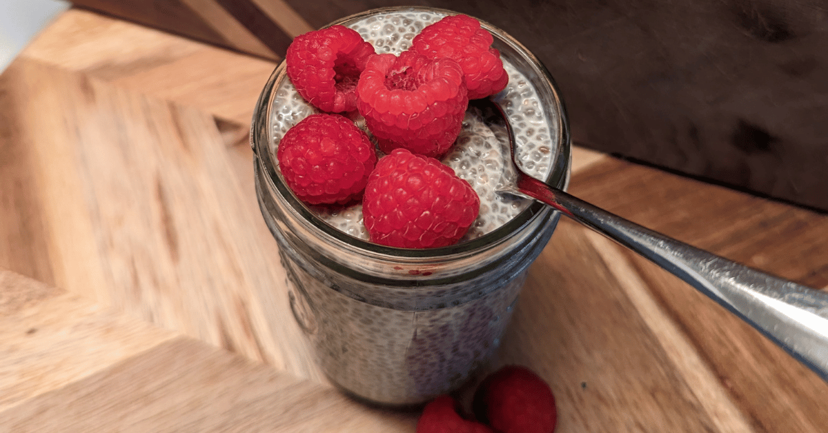 chia pudding in a mason jar with raspberries and a spoon