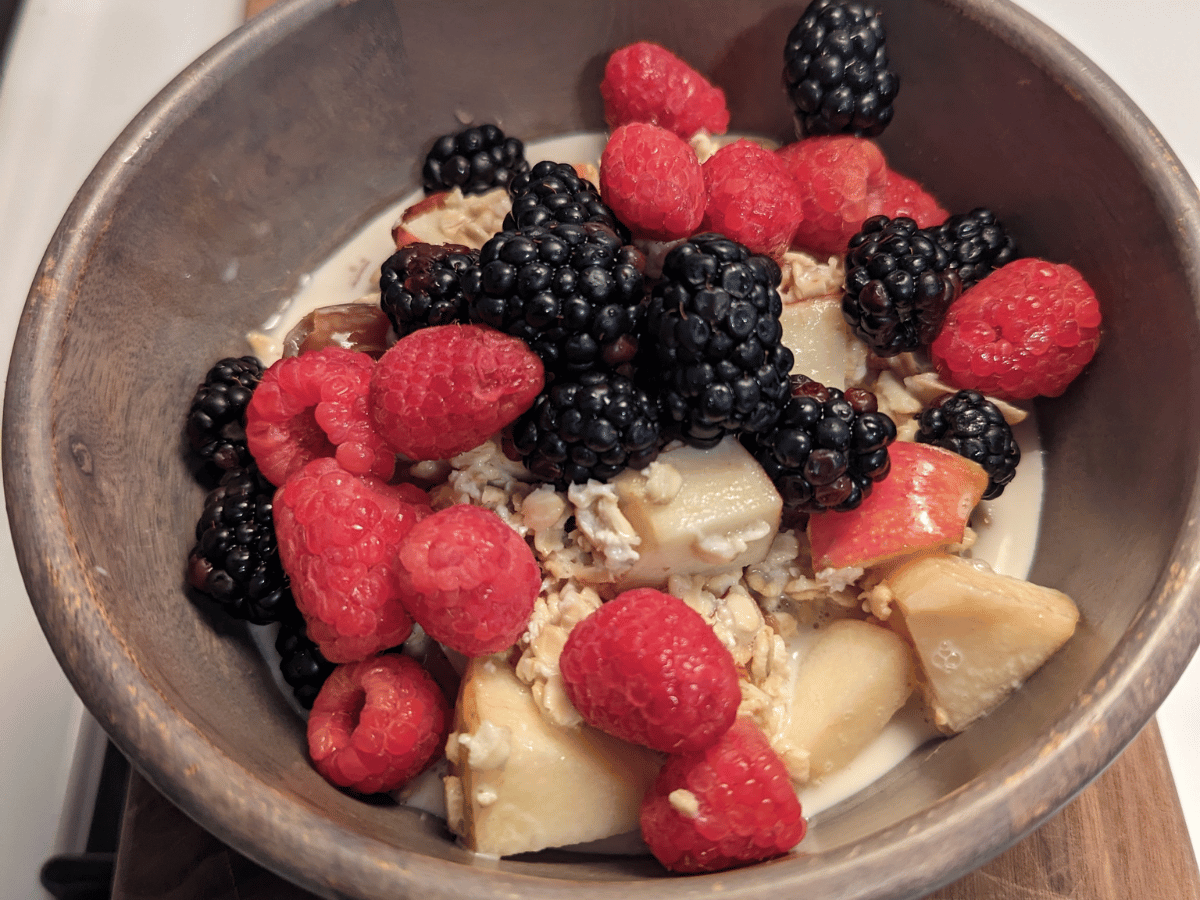 wood bowl with muesli and topping of fresh mixed berries